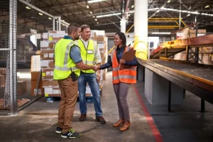 workers in a warehouse, discussing the best energy-efficient conveyor solutions for 2025