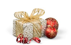 gold and white wrapped present with a gold bow sitting next to two gold and red Christmas ornaments and a small curl of red ribbon