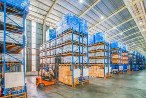 material handling warehouse with boxes on shelves and an orange forklift nearby