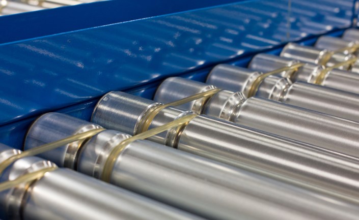 close-up of conveyor rollers against a blue background, illustrating synergy in material handling