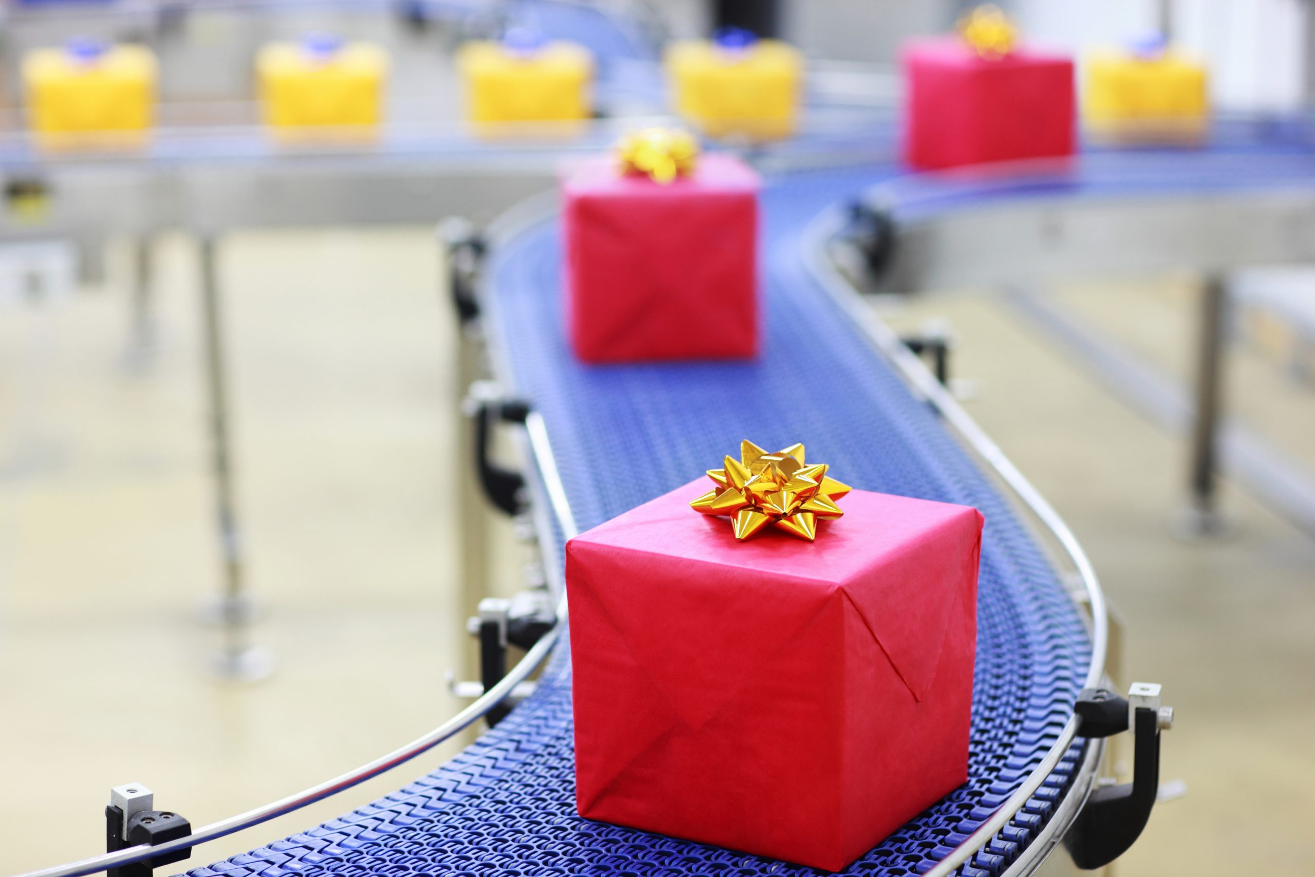 red gifts with gold bows on a blue conveyor